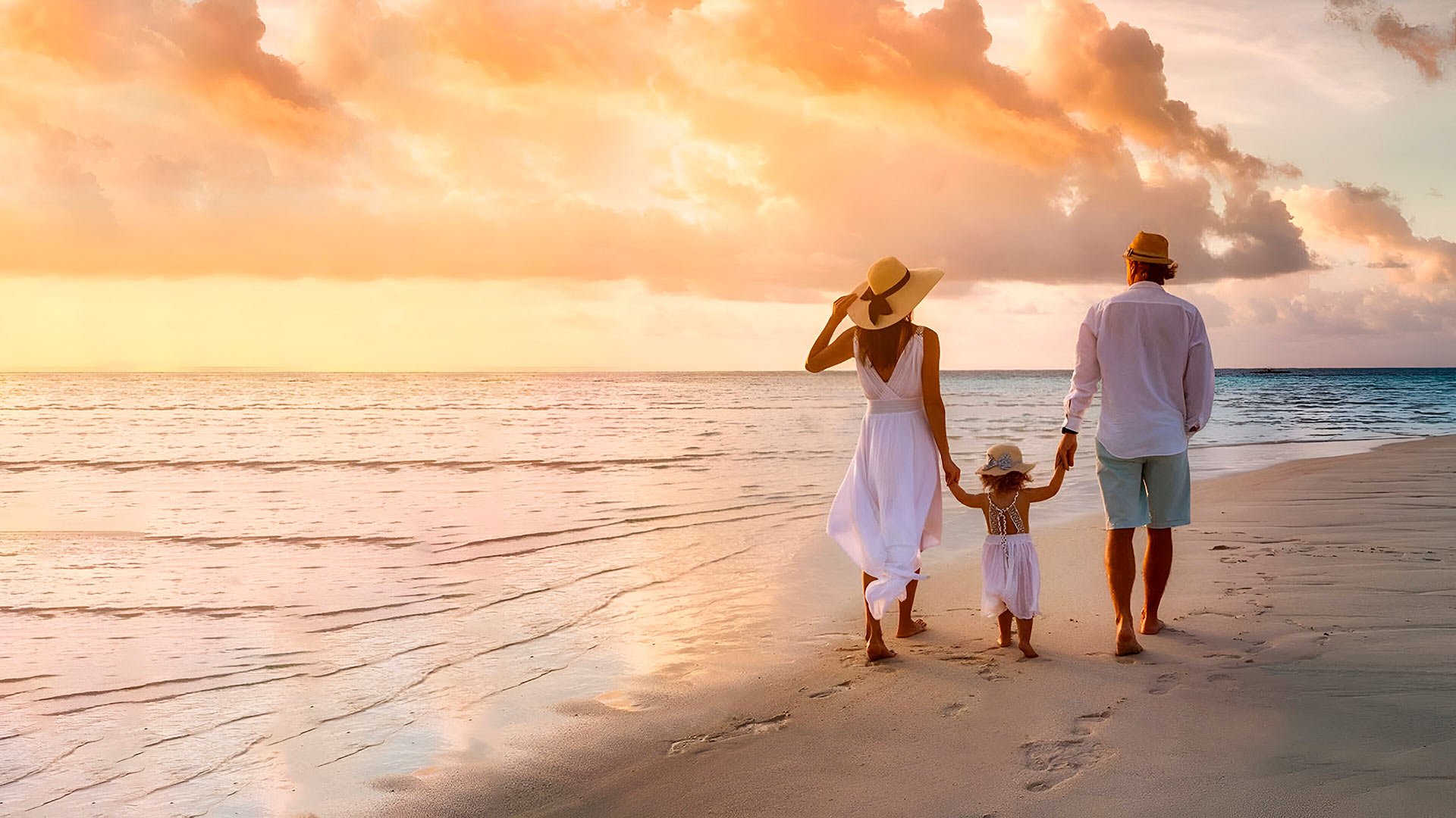 Familia caminando por la playa al atardecer