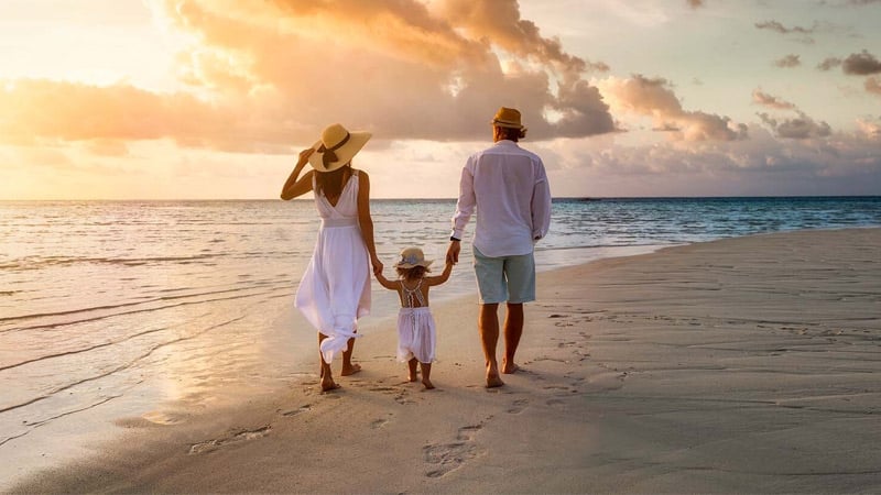 Familia caminando en la playa durante el atardecer
