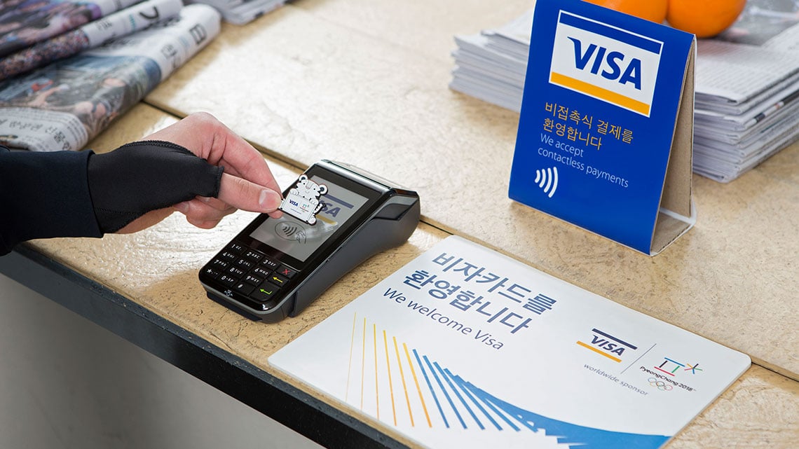 Person using a 2018 Olympic commemorative pin at contactless-enabled terminal to make purchase.