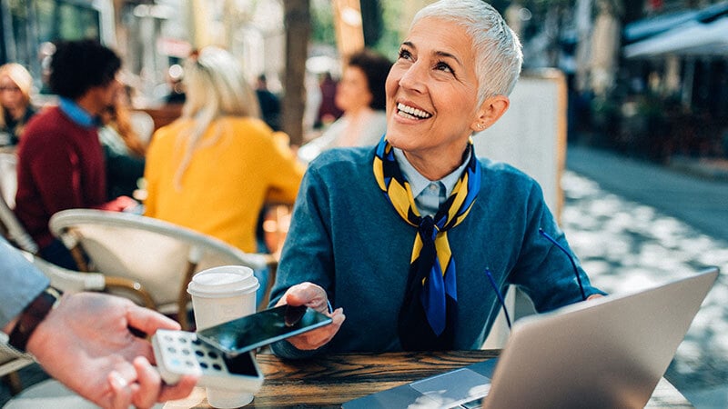 Woman paying with Visa phone at cafe exterior 