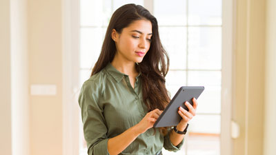 Mujer sentada en un banco mira su celular y come helado