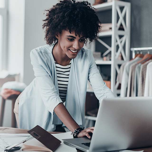 mujer en tienda de ropa trabajando en laptop