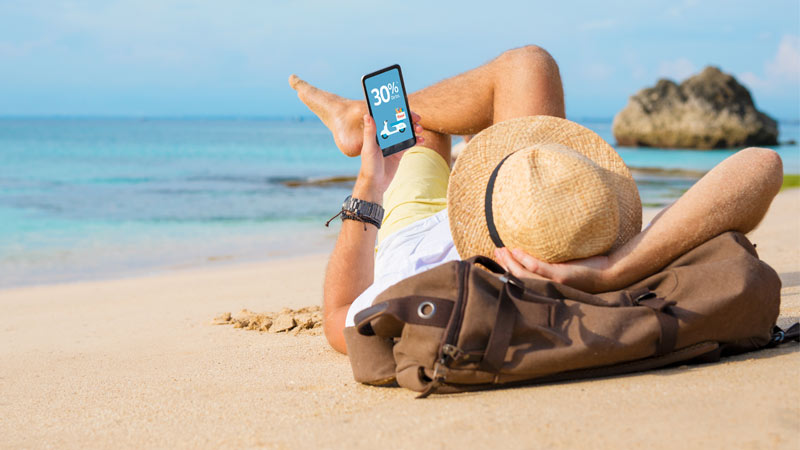 Hombre mirando su celular en la playa